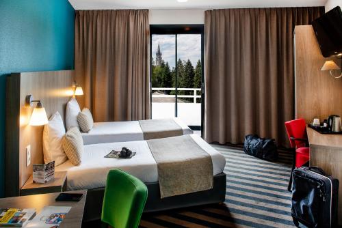 卢尔德全景酒店的配有一张床、一张书桌和一扇窗户的酒店客房