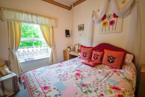 贝图瑟科伊德Gorphwysfa House B & B的一间卧室配有一张带红色枕头的床和一扇窗户