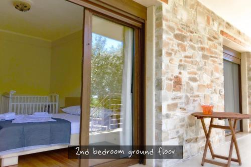阿斯特里斯Astris Traditional Private Villa的带玻璃门、床和阳台的客房