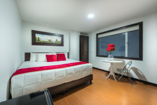 波哥大Hotel Bogota Resort的一间卧室配有一张带红色枕头的大床和窗户