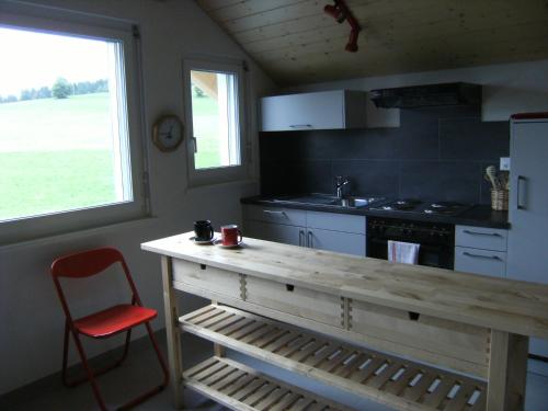La Côte-aux-Fées尼亚德尔住宿加早餐酒店的厨房配有木制柜台和红色椅子