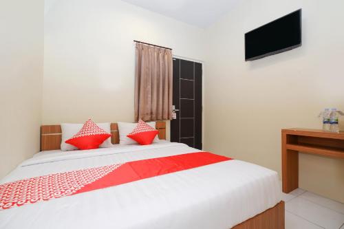 三宝垄Super OYO 1250 Unta Residence的一间卧室配有一张带红色枕头的床和电视。