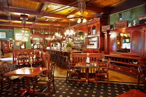 布雷达Parkhotel Mastbosch Breda的一间带木桌椅的餐厅和一间酒吧