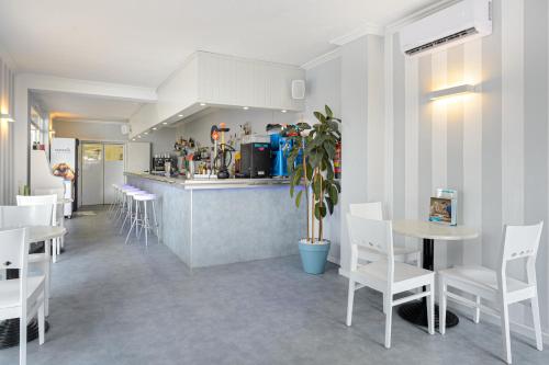 圣安东尼奥Hotel Apartamentos Vibra Central City - Adults only的餐厅设有白色的桌椅和柜台