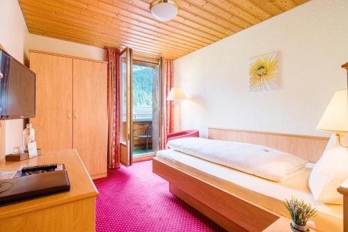 坎德施泰格瑞士博尼福品质酒店的一间卧室配有一张床、一张书桌和一台电视