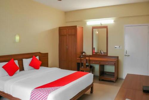 浦那Hotel Nandanvan Annexe的一间卧室配有一张带红色枕头的床和一张书桌