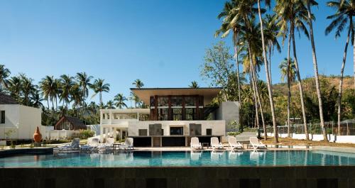 圣吉吉The Kayana Beach Lombok的一座带游泳池和棕榈树的房子