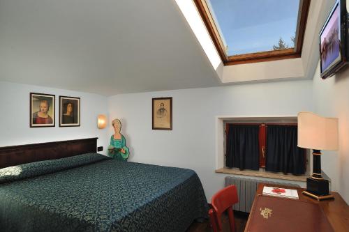 乌尔比诺波肯特酒店的一间卧室配有一张床、一张桌子和一个窗户。