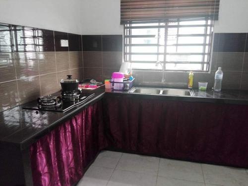 甲抛峇底Nurul Homestay的厨房配有水槽和炉灶 顶部烤箱