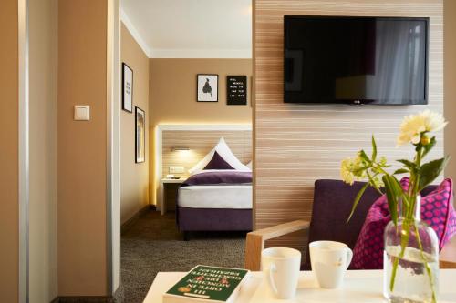 慕尼黑Hotel Mirabell by Maier Privathotels的一间酒店客房,配有一张床和一台墙上的电视