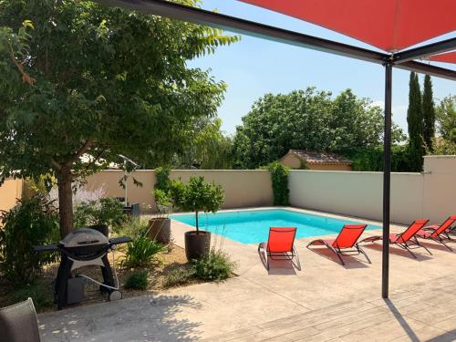 艾居厄河畔卡马勒La Maison de Caillette的一个带红色椅子和遮阳伞的游泳池