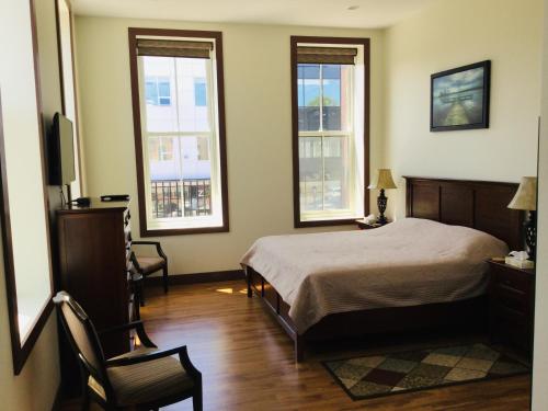 夏洛特顿Water Suites的一间卧室设有床、两扇窗户和一把椅子