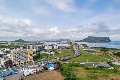 西归浦市Golden Tulip Jeju Seongsan Hotel的城市和海洋的空中景观