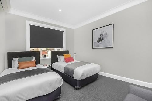 悉尼Horse and Jockey Hotel Homebush的一间卧室配有两张床和一张沙发。