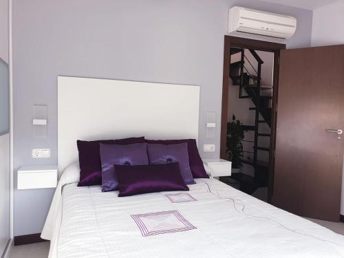 阿尔姆尼卡Bonita casa en Cotobro的一间卧室配有一张带紫色枕头的床和楼梯。