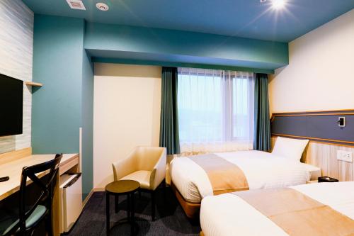熊本Hotel Wing International Select Kumamoto的酒店客房配有两张床和一张书桌