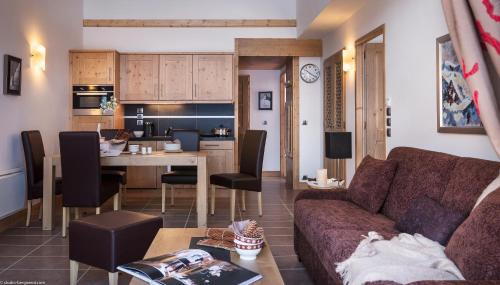蒂涅CGH Résidence Boutique Le Lodge des Neiges的客厅以及带沙发和桌子的厨房。