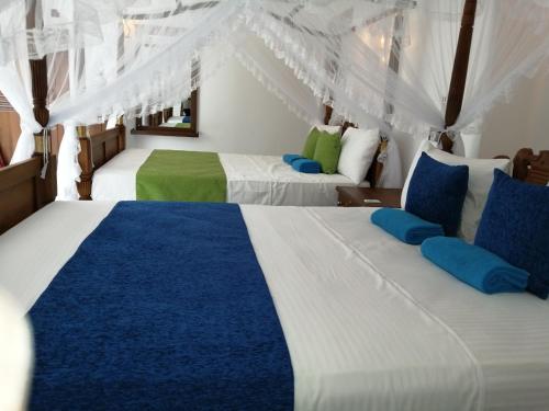 米瑞莎Suriya Homestay Mirissa的蓝色和白色的客房内的两张床