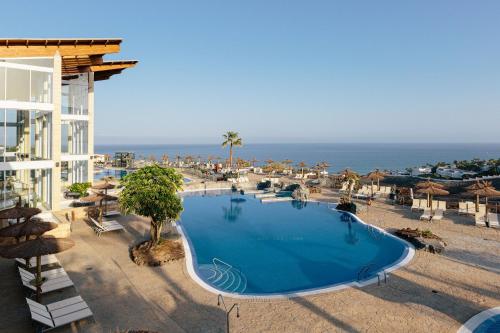 甘迪亚海滩Alua Village Fuerteventura - All Inclusive的一座大型游泳池,毗邻一座建筑和大海