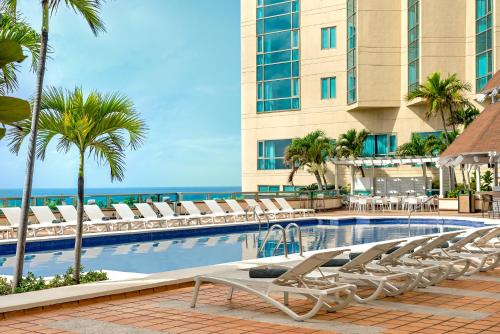 圣多明各圣多明各加泰罗尼亚酒店的一个带躺椅的游泳池和海洋