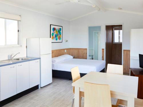 新月岬Crescent Head Holiday Park的一间设有床铺、厨房和桌子的房间
