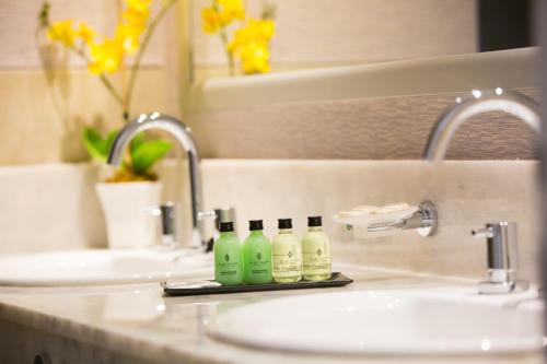 CharataPLATINUM HOTEL CASINO的浴室水槽,内有3瓶绿瓶
