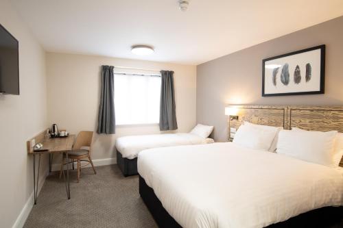 布拉克利Paisley Pear, Brackley by Marston's Inns的酒店客房配有两张床和一张书桌