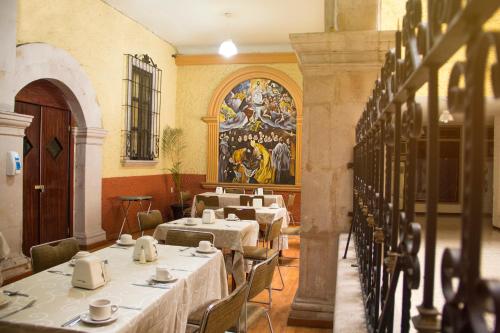 萨卡特卡斯Hotel Maria Benita的用餐室配有桌椅,墙上挂有绘画作品