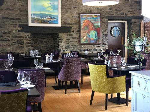 Port Charlotte夏洛特港酒店 的餐厅配有桌椅和紫色椅子