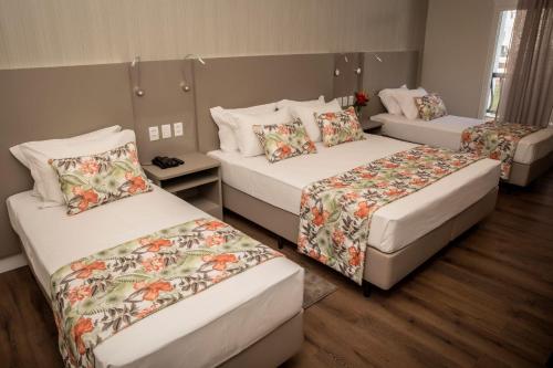 IretamaJardins de Jurema Convention & Termas Resort的客房设有3张带花卉图案的床铺。