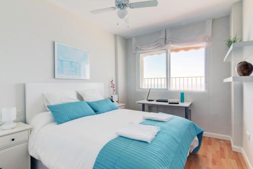 加的斯Apartamento Playa Victoria Cadiz的卧室配有带蓝色枕头的大型白色床