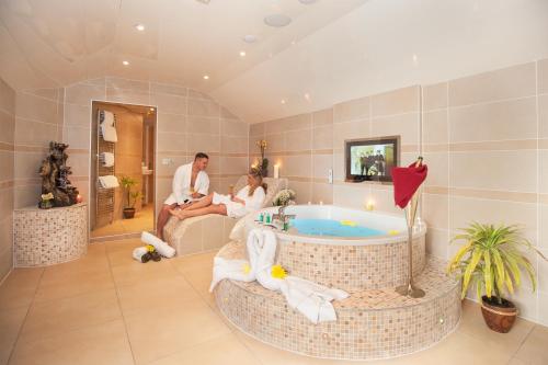 温德米尔Windermere Boutique Hotel Spa Suites & Hot Tubs的坐在带浴缸的浴室中的新娘和新郎