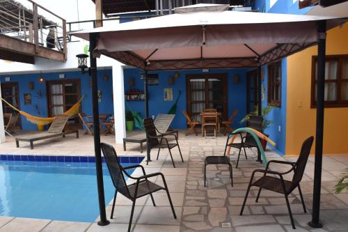 托鲁斯Pousada Amigos do Vento的游泳池旁的天井配有椅子和遮阳伞。