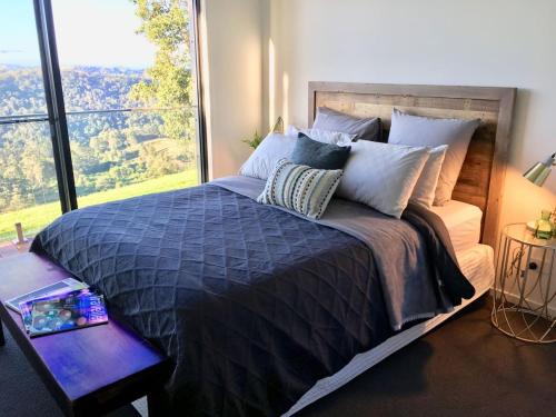 马莱尼Scandinavian Cabin - Maleny - One Bedroom的一间卧室设有一张大床和大窗户
