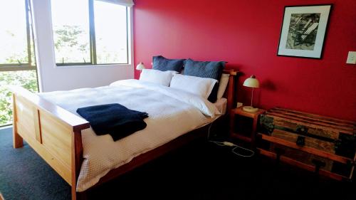 奥克兰Shelly Beach Studio, Waiheke Island的一间卧室设有一张红色墙壁的大床
