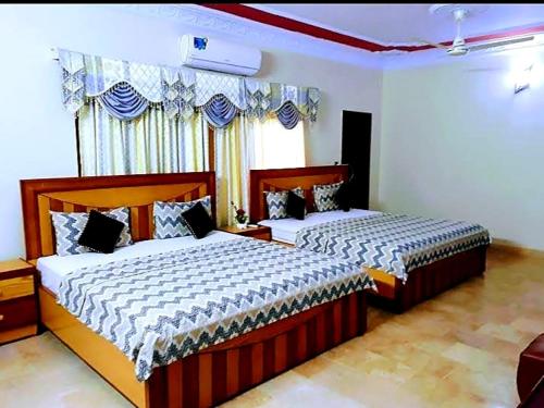 卡拉奇Gulshan Palace Near Millennium Mall的一间卧室设有两张床和窗户。