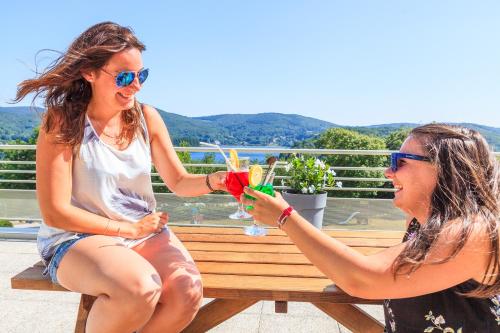NagesLes Fées du lac ***的两个女人坐在长凳上喝着饮料