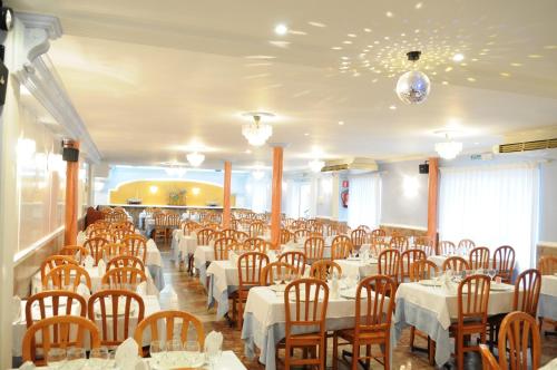 圣卡洛斯拉腊皮塔坎玛丽尼斯旅馆的用餐室配有白色的桌子和木椅