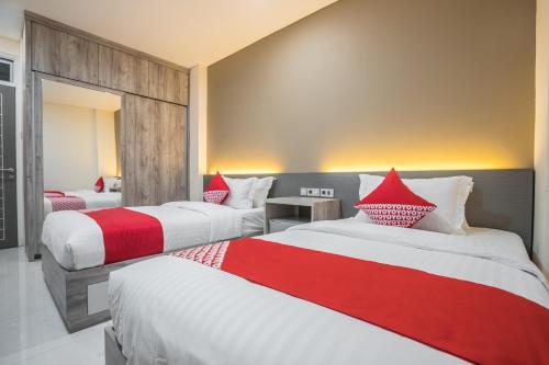 雅加达OYO 1487 Residence Khoe的酒店客房带两张红色和白色的床单