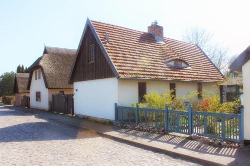 KrumminHaus am Wiek的白色的房子,有黑色的屋顶和栅栏