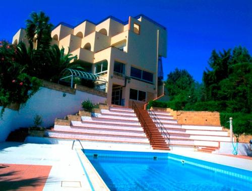 克罗托内太阳神酒店的一座带楼梯的建筑,前面设有一个游泳池