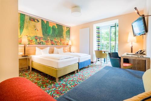 劳尔Boutique Hotel Bundschuh 3 Sterne Superior的一间卧室配有两张床、一张桌子和一台电视。