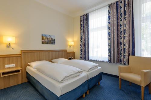 吕贝克Mercure Hotel Luebeck City Center的酒店客房,配有两张床和椅子