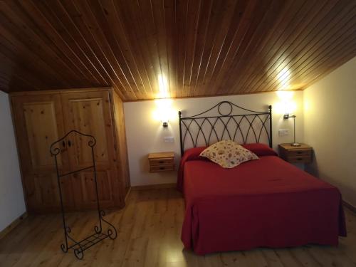 戈索尔Hostal Cal Franciscó的一间卧室设有红色的床和木制天花板
