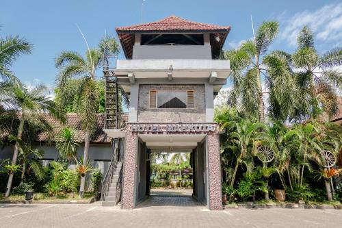 外南梦Hotel Mahkota Plengkung by ecommerceloka的一座有楼梯的建筑,通往一座棕榈树建筑