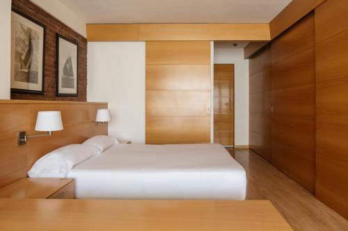 巴塞罗那韦洛公寓的卧室配有白色的床和木制橱柜。