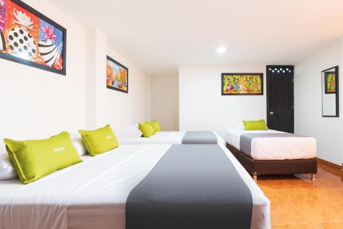 波哥大Ayenda 1045 Boutique Aeropuerto的酒店的客房 - 带两张带绿色枕头的床