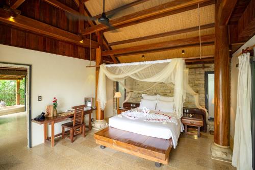 芽庄The Trang Villas的一间卧室配有一张天蓬床、一张桌子和一张桌子