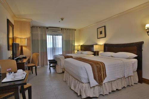 麦克坦麦克坦皇冠丽晶套房酒店的酒店客房配有两张床和一张书桌
