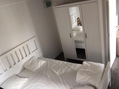 布列登Camping Thalassa Belgische Kust Vakantiehuis的卧室配有白色的床和镜子